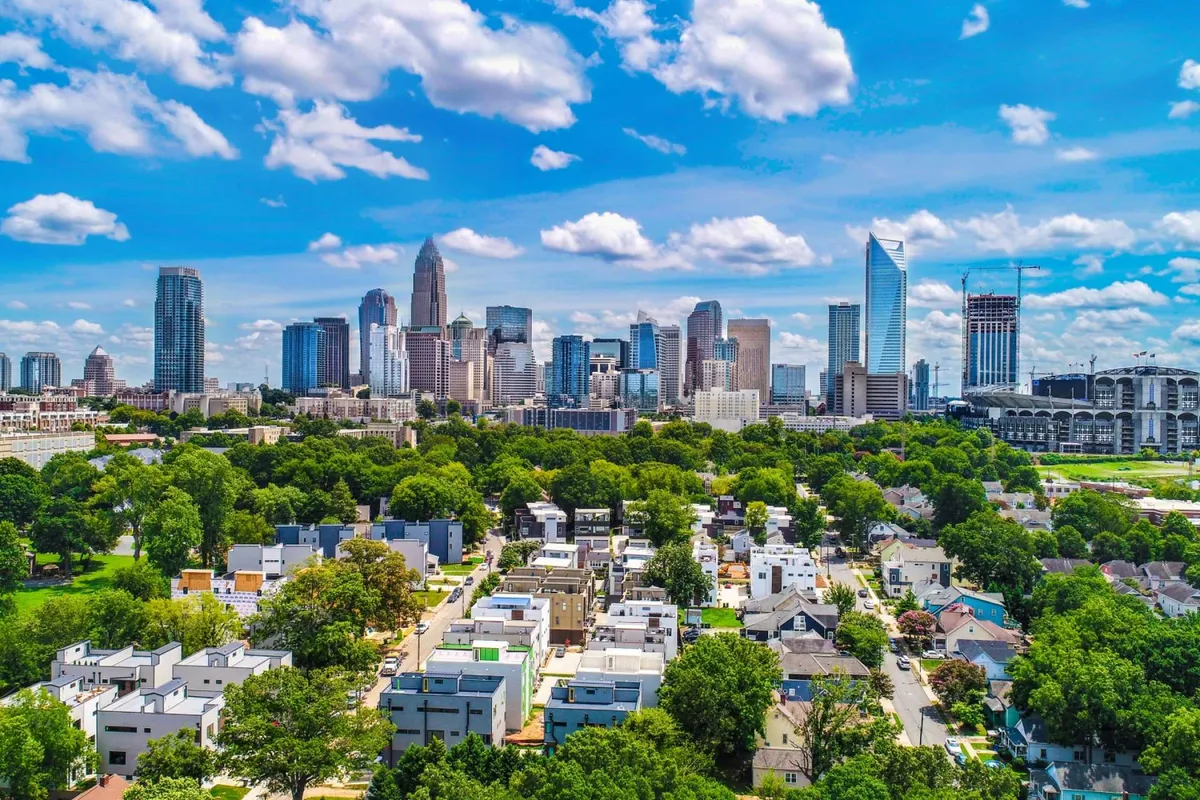 A panoramic view of the city skyline set against green parks and residential areas beneath a dramatic sky. The image captures both urban excitement and nearby green spaces, hinting at the convenience of city amenities within reach of natural retreats.