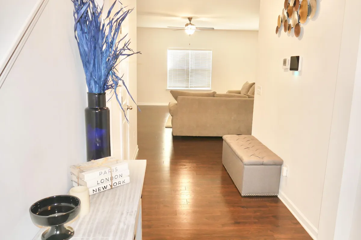This image highlights a stylish entryway with a blue decorative plant, a modern bench, and a view into the living room. The area is inviting and bright, suggesting an easy transition from indoor comfort to outdoor adventures. The welcoming vibe hints at a home that’s ready for humans and pets alike, with features that make coming and going with your furry companion convenient.