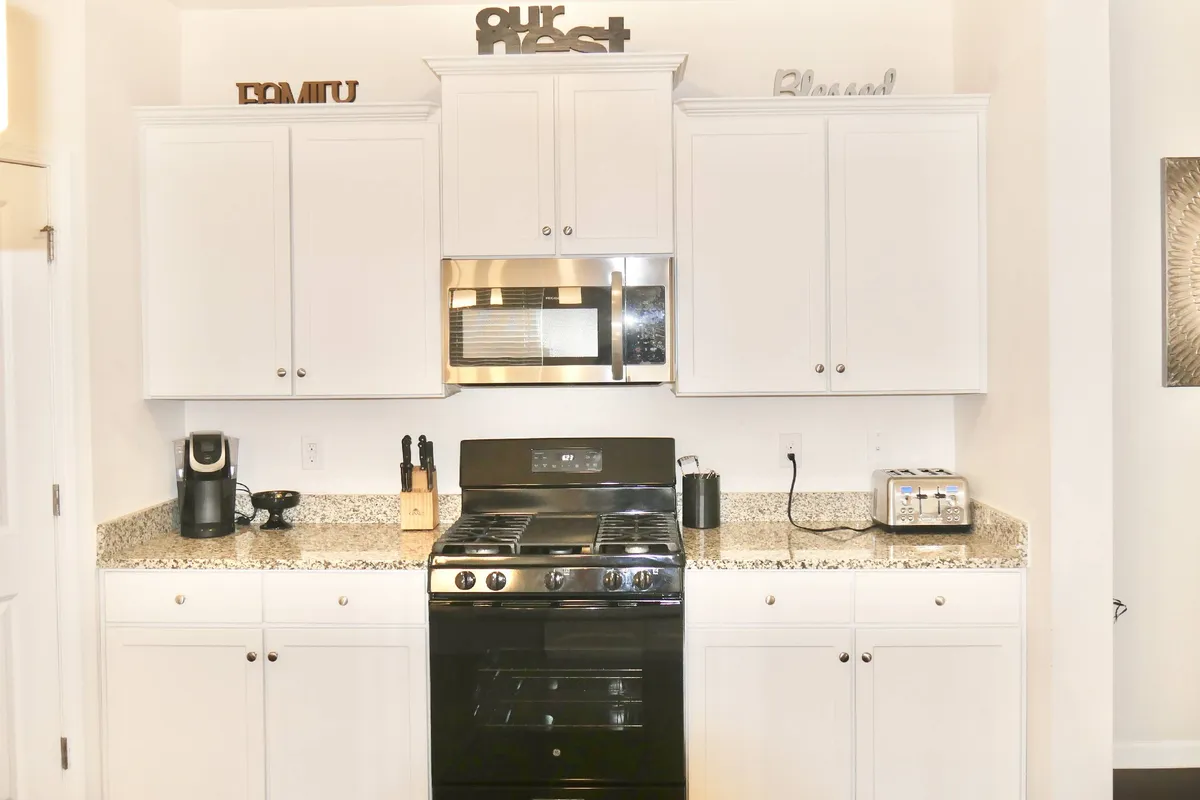 A well-equipped kitchen featuring a stove, microwave, coffee maker, and decorative signs. Everything is organized and clean, suggesting attention to detail and readiness for guest use, whether for a short visit or extended stay.