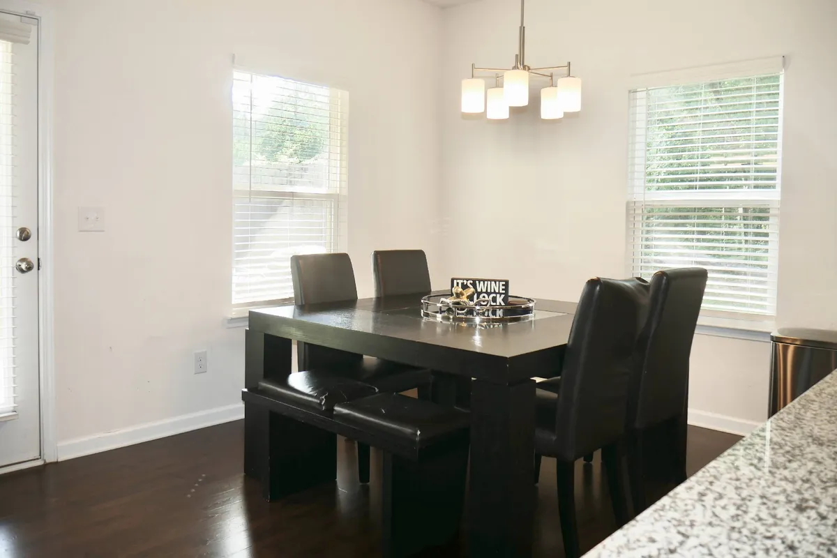 A comfortable dining area featuring a large dining table under a chandelier, with wine decor enhancing the festive, intimate atmosphere. The table is set for family meals or dinner parties.